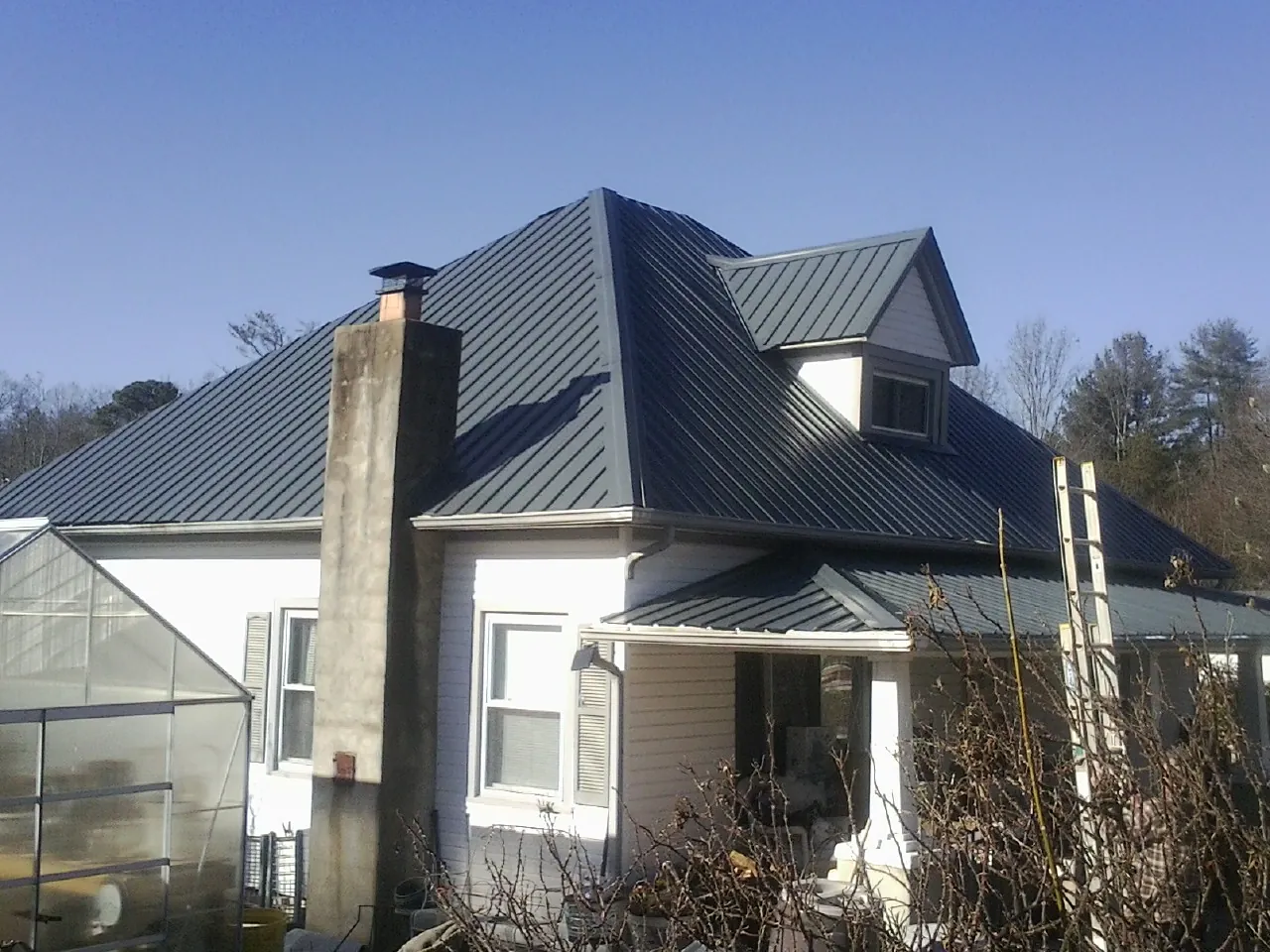 Dark blue standing seam metal roof on a white farmhouse with dormer — Slate & Tile Roof Repair by Roofing Brothers in Wooster
