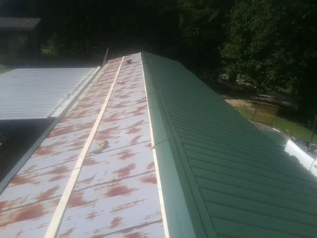 Old rusted panels beside newly installed green metal roofing — Wind Damage Roof Repair by Roofing Brothers in Wooster