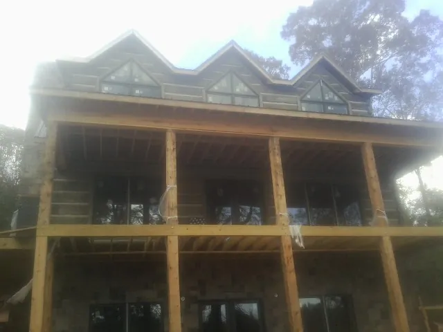 Dormers and porch framing on a large log home under construction — Roof Coating work by our crew in Wooster