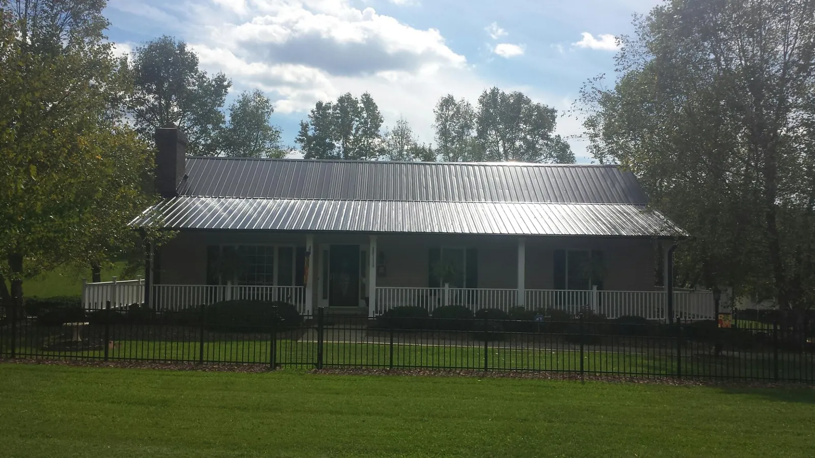 Gray metal roof on a brick ranch with a full width front porch — Gutter Guard Installation work by our crew in Wooster