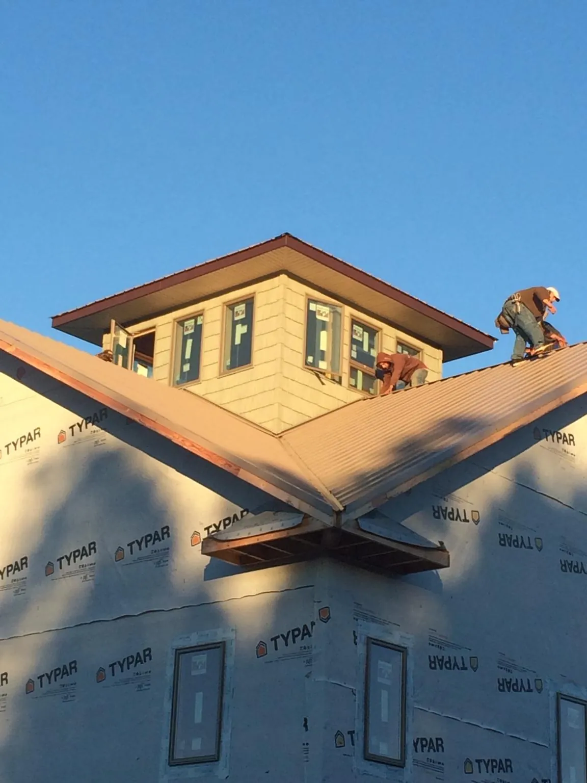 Roofers working around a rooftop cupola on a new metal roof at sunset — Roof Waterproofing in Wooster by Roofing Brothers